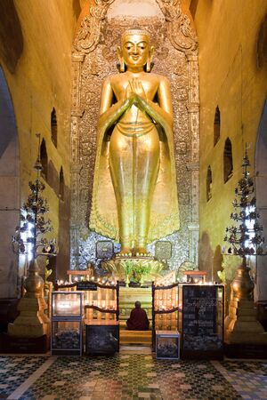 Gold Buddha statue with praying monk in Ananda temple, Bagan, Burma.のeditorial素材