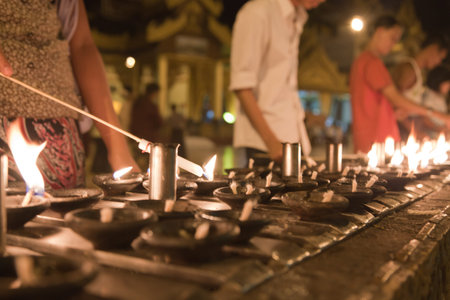 The biggest Buddhist temple Shwedagon pagoda at night lighting with praying Buddhist people,...