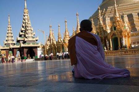 The biggest Buddhist temple Shwedagon pagoda with praying Buddhist monk woman, Rangoon, Burma.の写真素材
