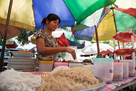 BURMA, RANGOON - FEBRUARY 12, 2011: Street local restaurant with woman preparing noodle food.のeditorial素材