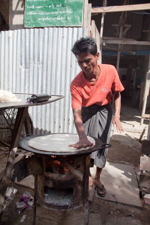 BURMA, RANGOON - FEBRUARY 12, 2011: Man on the street is baking local prepared food.のeditorial素材