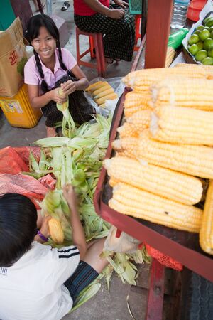 BURMA, RANGOON - FEBRUARY 12, 2011: Woman is preparing corn for sale on street food market.のeditorial素材