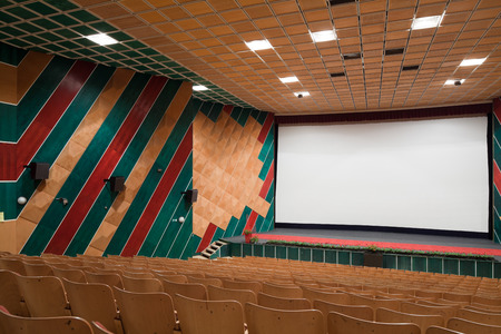 PR (property release) available. Empty cinema auditorium with line of chairs and projection screen. Ready for adding your own picture. Side view.の写真素材