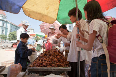 BURMA, RANGOON - FEBRUARY 13, 2011: Young boy is selling on street local market fried pork offals.のeditorial素材