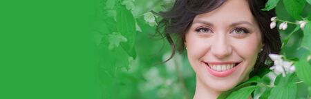 Springtime. Woman in spring garden. Young girl in spring landscape background. Female face with healthy skin and healthy teeth. Beauty clinic skincare organic natural spring concept bannerの写真素材