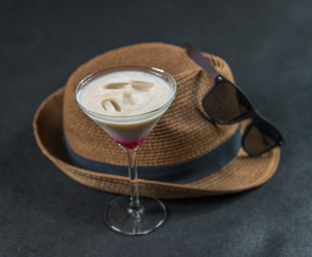 colored drink, a combination of red, beige and violet, martini glass, brown sunglasses, brown stylish hat, party setの写真素材