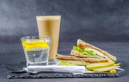 set consisting of two sandwiches malted bread with vintage cheddar cheese, pickles, red onion, tomato, lettuce, water and coffee latte, breakfast setの写真素材