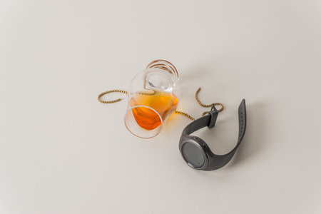 Overturned single malt whiskey glass, on white, with gold chain and smartwatch, white backgroundの写真素材