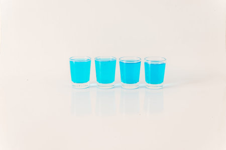 Four glasses of blue kamikaze, glamorous drink, mixed drink poured into shot glasses, party setの写真素材
