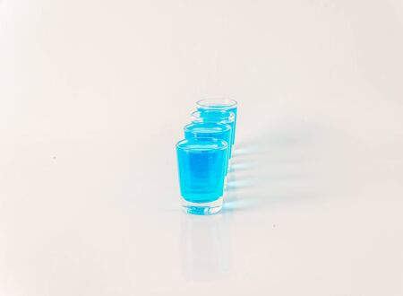 Four glasses of blue kamikaze, glamorous drink, mixed drink poured into shot glasses, party setの写真素材