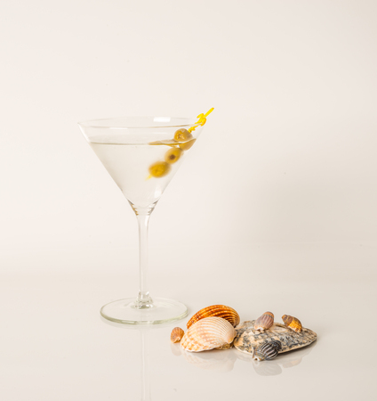 Drink in martini glass, martini drink with green olives, seashells, martini setの写真素材