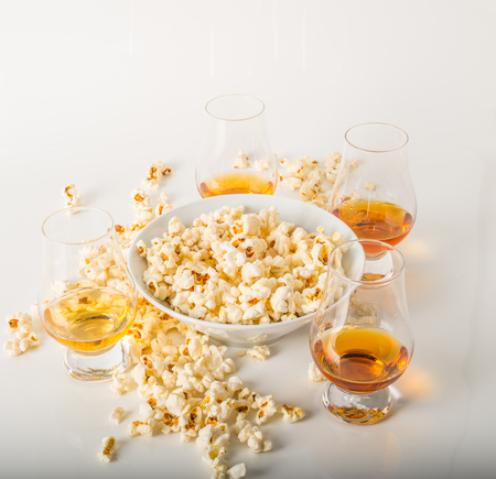 set of glasses of single malt whisky, salty popcorn in a bowl and rozypane around, party setの写真素材