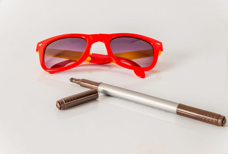 Brown marker pen  with red sunglasses, color  highlighter, school tools, white background