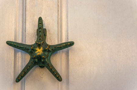 Old wooden door to house with a brass knocker in the shape of a starfish, sea element, vintage decorの写真素材