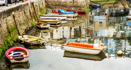 Boats anchored in a harbor, in the background stone promenade, seaside, cloudy day