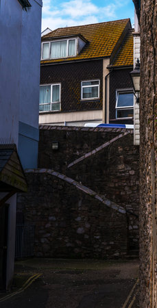 Narrow passage from the back of buildings in seaside town, old architecture and interesting stairs, stone walls, historic buildings, english townの写真素材