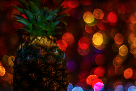 Whole pineapple fruit on the background of blurred lights, bokeh background, party nightの写真素材