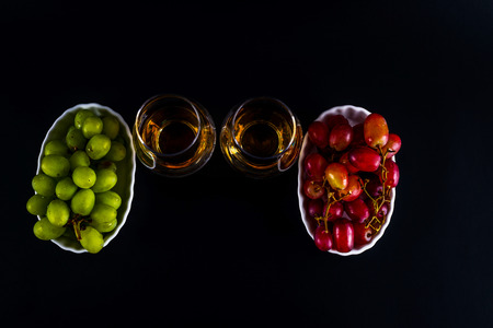 single malt tasting glasses, single malt whisky in a glass, white and red grapes in white bowls, black  backgroundの写真素材
