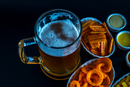 Set of snacks with dip and pint of beer, crunchy snacks, good food, black backgroundの写真素材