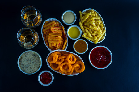 set of snacks with different dips and a single malt in a glass, crunchy snacks in a bowls, good food, black backgroundの写真素材