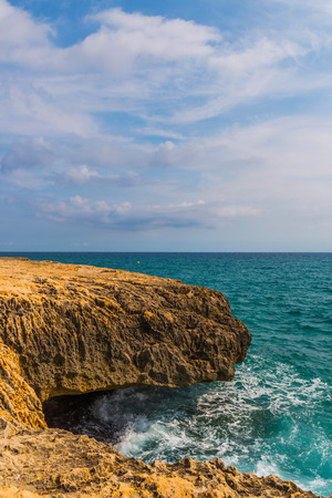 high cliff above the sea, summer sea background, many splashing waves and stone, sunny dayの写真素材