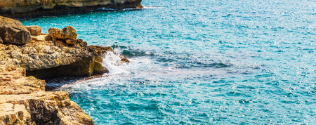 high cliff above the sea, summer sea background, many splashing waves and stone, sunny dayの写真素材