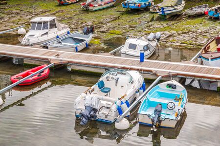 Boats  in a little harbor during an outflow, low water level, fishing industryの写真素材