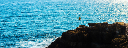 high cliff above the sea, summer sea background, many splashing waves and stone, sunny dayの写真素材