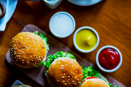 mini burgers with meat, vegetables, cheese and other toppings, bread sprinkled with sesame seeds, mini fast food, tasty setの写真素材