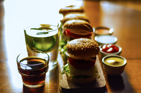mini burgers with meat, vegetables, cheese and other toppings, bread sprinkled with sesame seeds, mini fast food, tasty setの写真素材