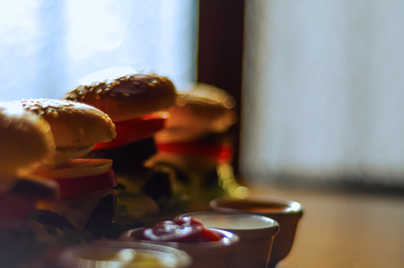 mini burgers with meat, vegetables, cheese and other toppings, bread sprinkled with sesame seeds, mini fast food, tasty setの写真素材
