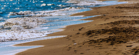 Close up of the sea water affecting the sand on the beach, sea waves calmly flowing sand, relaxing view, summer timeの写真素材