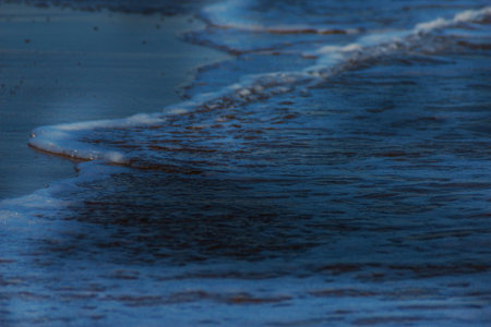 close up of the sea water affecting the sand on the beach, sea waves calmly flowing sand, relaxing view, summer timeの写真素材