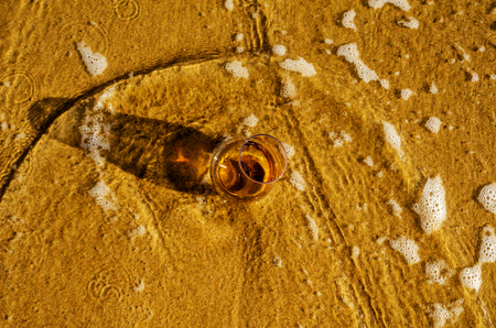 A glass of whiskey single malt on the sand washed by the waves, a glass of tasting, relax on the beach, vacationの写真素材