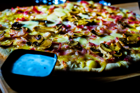 Delicious pizza with bacon, ham, mushrooms and mozzarella on a thin crust, traditional dishの写真素材