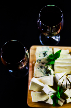 Red wine and set of different cheeses on a wooden board, delicious snack, healthy and exclusive foodの写真素材