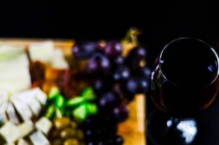 Red wine and set of different cheeses on a wooden board, delicious snack, healthy and exclusive foodの写真素材