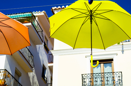 Colourful umbrellas urban street decoration. Hanging colorful umbrellas over blue sky, tourist attraction, sunny dayの写真素材