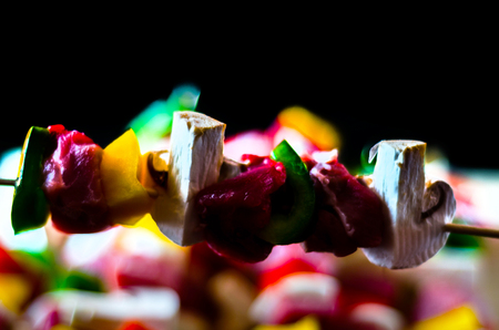 skewers with meat and vegetables prepared for grilling on a wooden board, colorful and tasty dishの写真素材