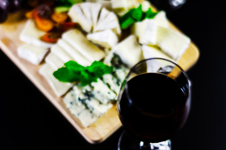 Red wine and set of different cheeses on a wooden board, delicious snack, healthy and exclusive foodの写真素材