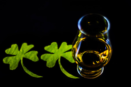 Single malt whisky in a glass of tasting with decoration for St. Patrick's day, green clover symbol for Irish holiday, festiveの写真素材