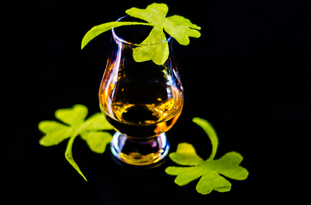 Single malt whisky in a glass of tasting with decoration for St. Patrick's day, green clover symbol for Irish holiday, festiveの写真素材