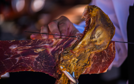 Professional butcher slicing jamon serrano, traditional Spanish ham, meatの写真素材