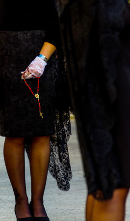 Rosary held by a woman in a black dress and white gloves, symbol of faith, christianityの写真素材