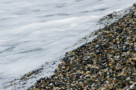 Pebble beach washed by sea waves, small and various stones forming the shore, natureの写真素材