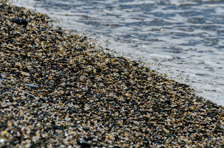 Pebble beach washed by sea waves, small and various stones forming the shore, natureの写真素材