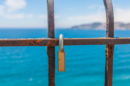 Rusty padlock attached to a balustrade by the sea, a traditional way of showing love, relationshipの写真素材