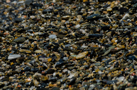 Pebble beach washed by sea waves, small and various stones forming the shore, natureの写真素材