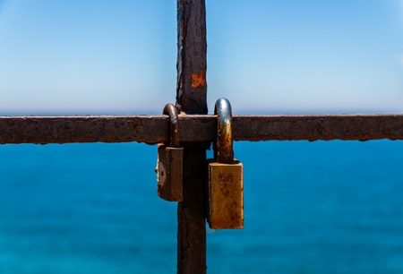 Rusty padlock attached to a balustrade by the sea, a traditional way of showing love, relationshipの写真素材