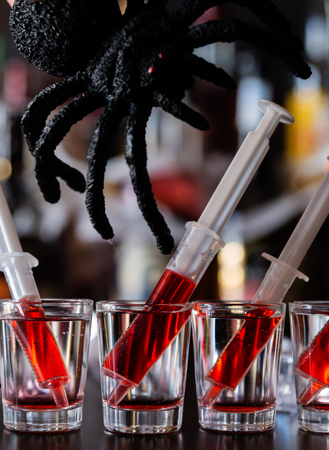 Creepy Halloween party cocktails with spider and syringes of grenadine syrup as blood, shot drinks at party, scary barの写真素材